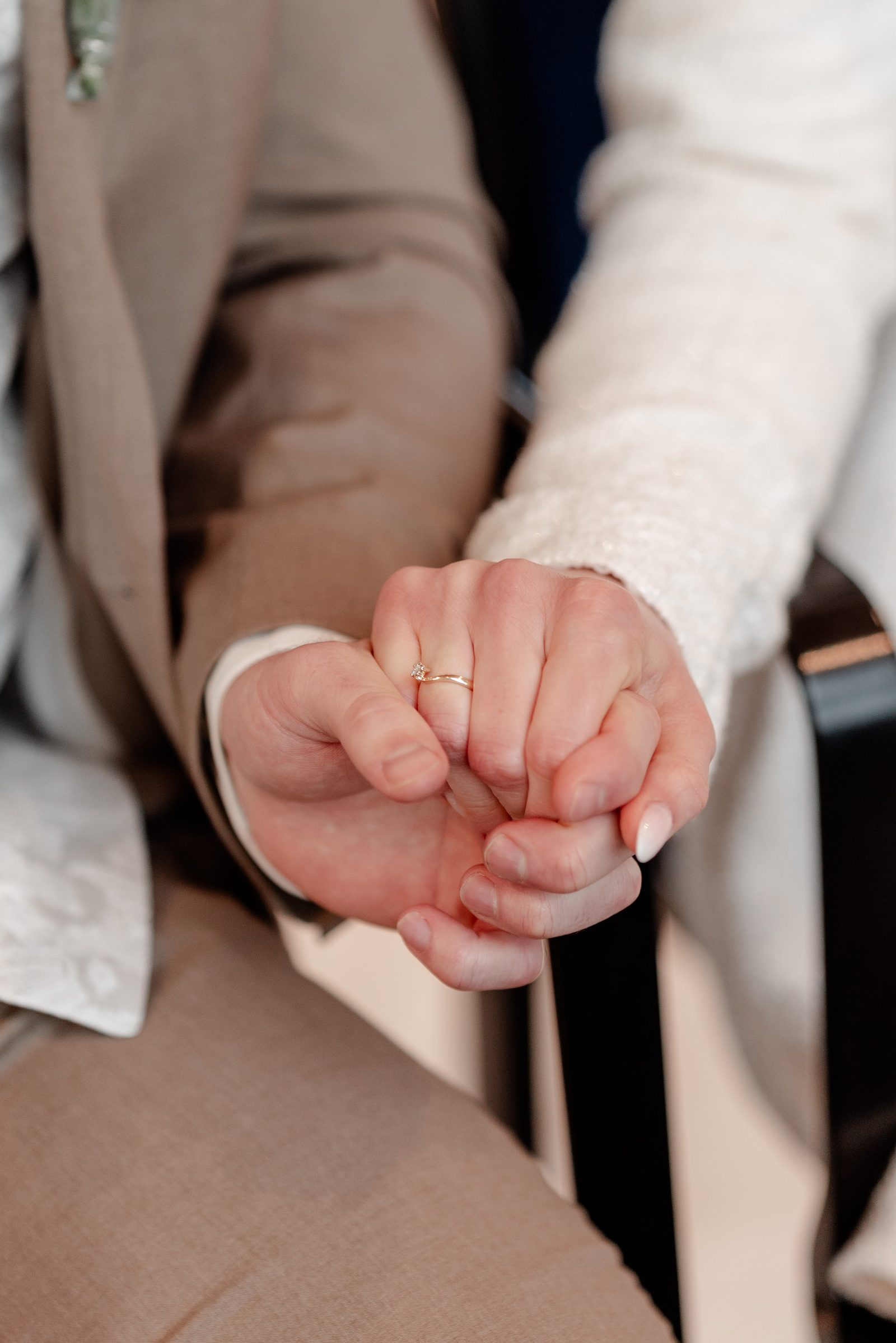 Nahaufnahme: Der Bräutigam hält die Hand der Braut, an ihrem Finger der neue Ehering