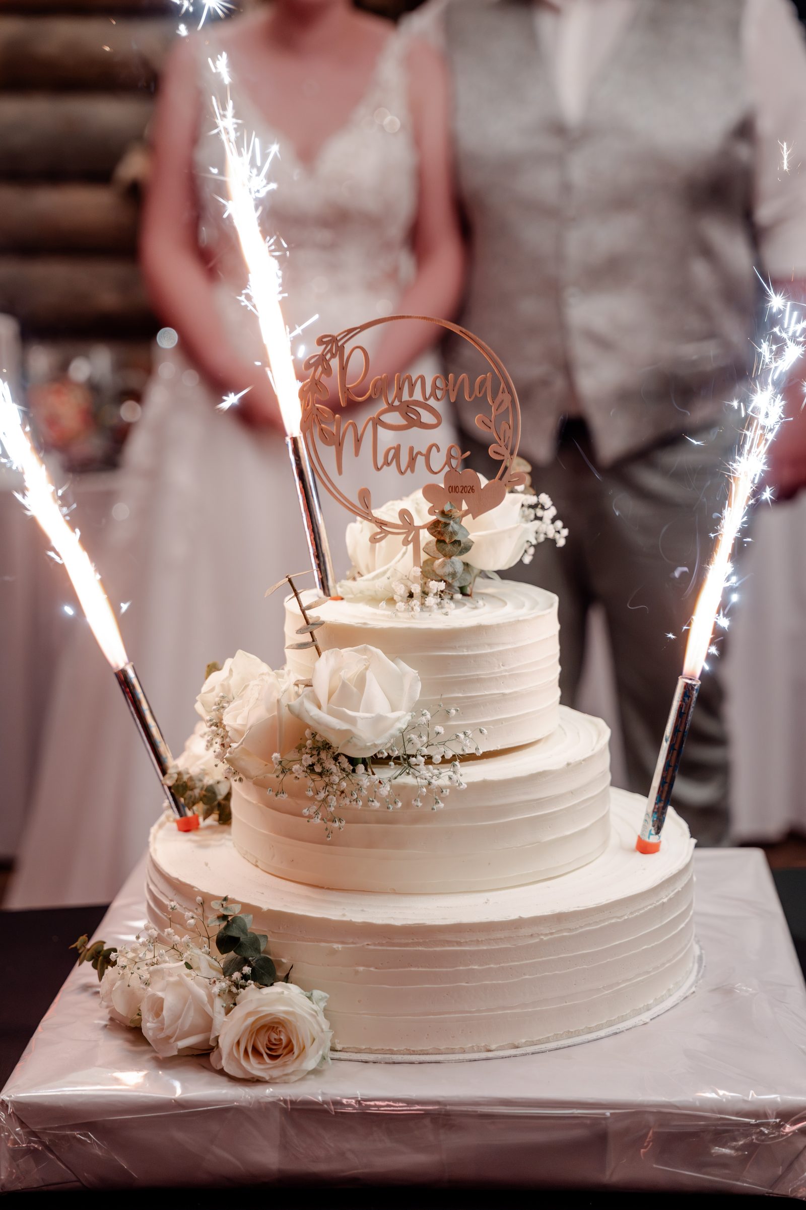 Die Hochzeitstorte mit Wunderkerzen und einem Topper mit den Namen des Paares