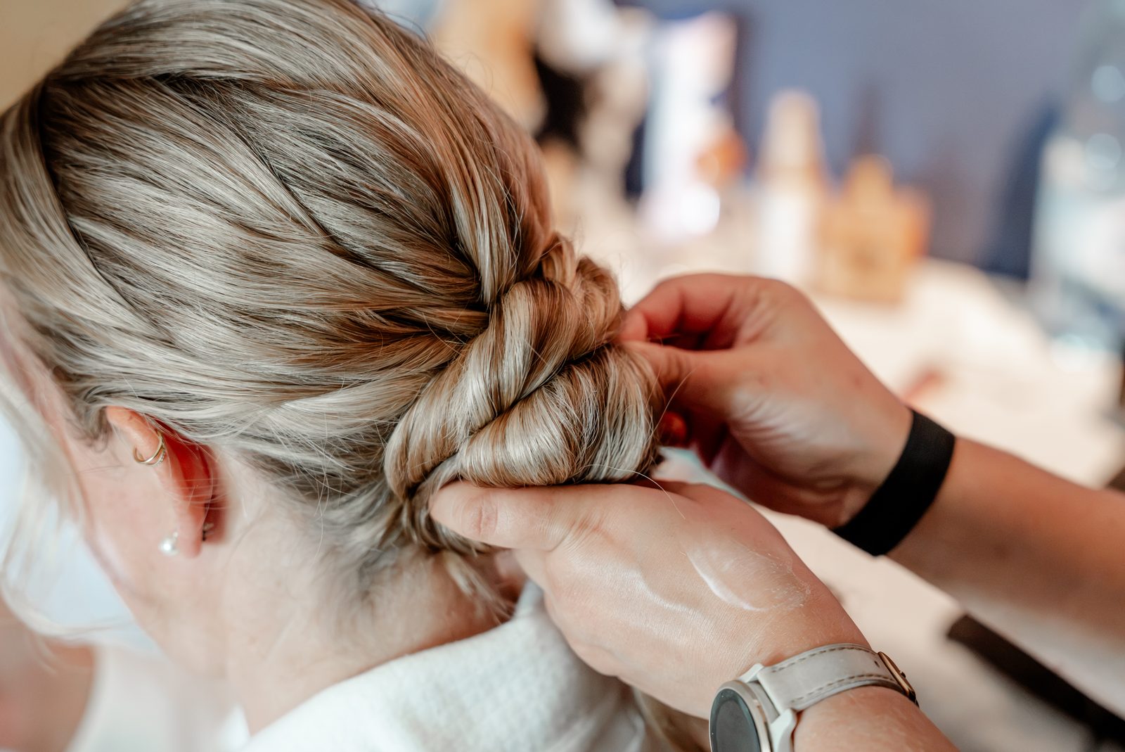 Vorbereitung: Hände stecken den geflochtenen Haarknoten der Braut fest