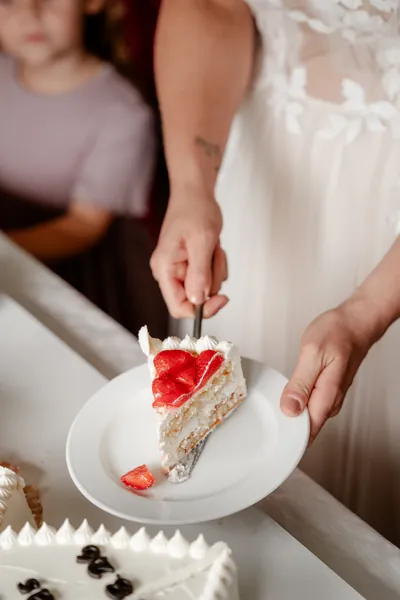 Tortenanschnitt: Die Braut legt ein Stück Erdbeertorte auf einen Teller