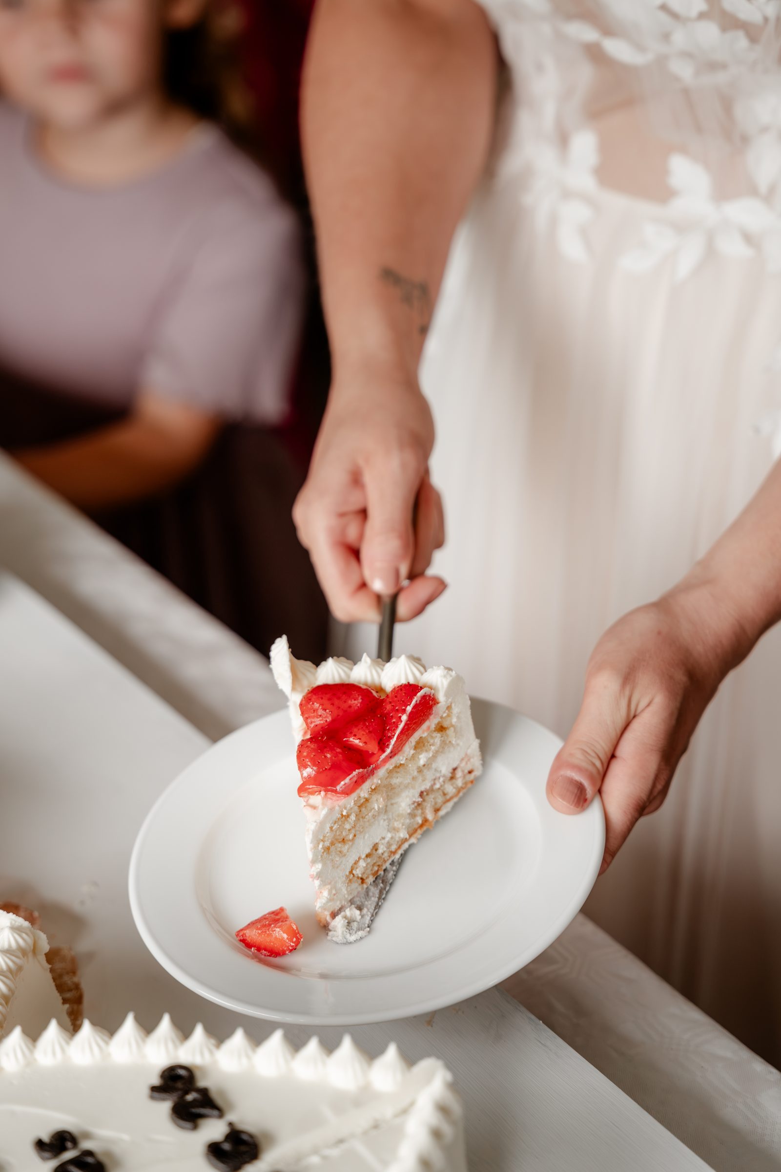 Tortenanschnitt: Die Braut legt ein Stück Erdbeertorte auf einen Teller